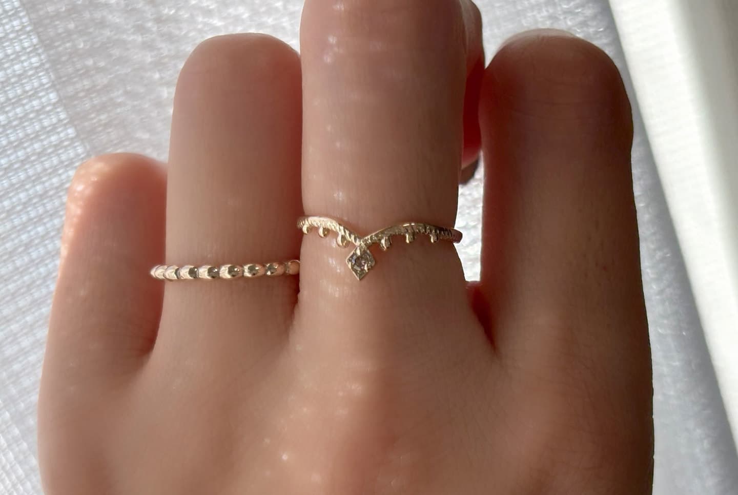 K10製のブラウンダイヤが輝く指輪、Veiled TikkaEllipse Harmonyを中指と薬指に着用している写真