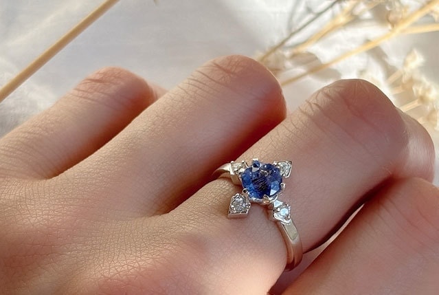 compassシリーズより、ブルーのカラーチェンジフローライトが中石のCelestiaを指に着用している写真。