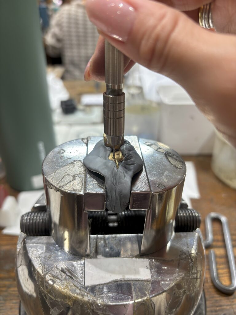 彫刻台でジュエリーに石留めをするためにピンバイスで穴あけをしている写真。